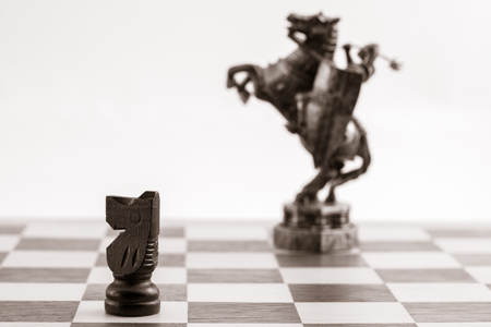 Classic black knight and the same piece in the form of medieval figure on the background. Selective focus on classic pieceの写真素材