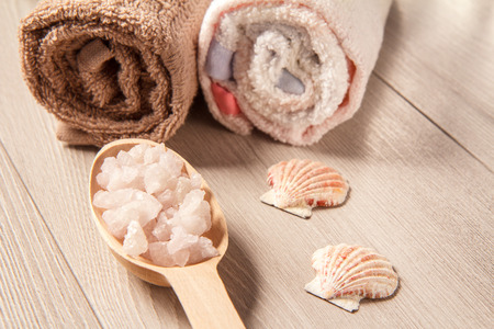 Wooden spoon with white sea salt for bathroom procedures with towels on the background. Spa products and accessoriesの写真素材