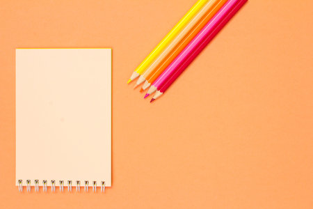 Book, scissors, notebook, color pencils and compass on pink background. Top view with copy space....
