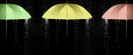 Green, yellow and red umbrellas under raindrops with black background. Business and fashion concept.の写真素材