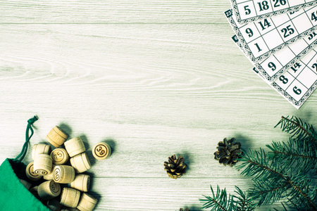 Board game lotto. Wooden lotto barrels with bag and game cards, Christmas fir tree branches and cones on wooden boards. Top view. Color toning effect.の写真素材