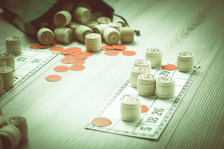 Board game lotto. Wooden lotto barrels with bag, game cards and red chips for a game in lotto. Shallow depth of field. Color toning effect.の写真素材