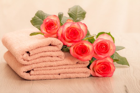 Stack of soft terry towels with red rose flowers on pink backgroundの写真素材