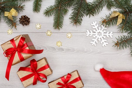 Christmas decoration. Santa's hat, gift boxes, fir tree branches with cones and Christmas toys on gray boards.の写真素材