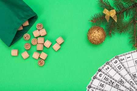 Board game lotto. Wooden kegs with bag and game cards for a game in lotto, Christmas fir tree branch and toy ball on greenの写真素材