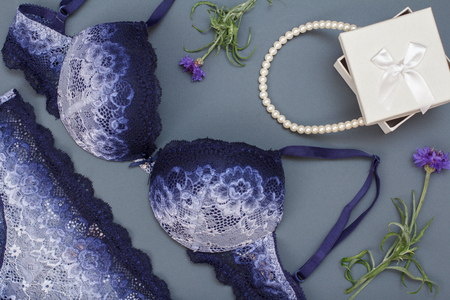 Beautiful, blue lace bra and panties with gift box and beads on gray background. Women sexy underwear set. Romantic lingerie for temptation. Valentine's Day concept.の写真素材