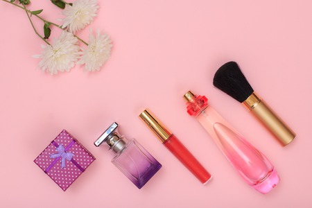 Gift box, bottles of perfume, brush and flowers on a pink background. Women cosmetics and accessories. Top view.の写真素材