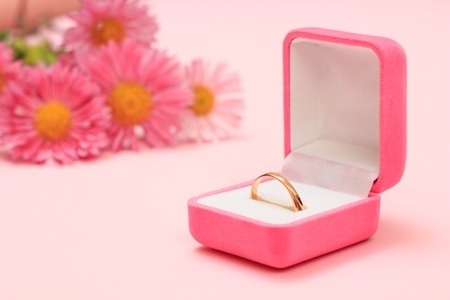 Golden ring in a box and flowers on a pink background. Women jewelry and accessories.の写真素材
