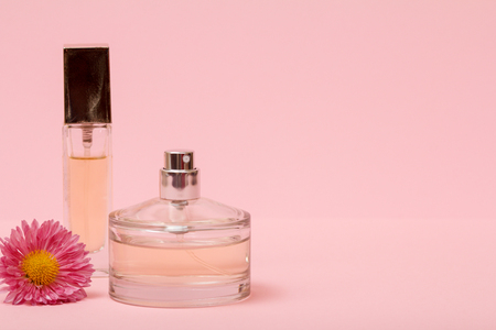 Bottles with women perfume and flower bud in a pink background with copy space. Women products.の写真素材