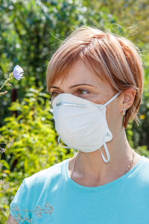 Woman in protective mask trying to fight allergies to pollen.の写真素材