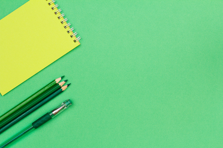 Notebook, color pencils and pen on green background. Top view with copy space. Back to school concept. School supplies.の写真素材