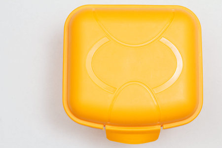 Yellow plastic lunch box on white background. Top view.