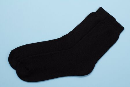 Pair of black warm woolen men socks on a blue background, Top view.の写真素材