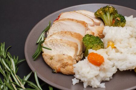 Baked chicken breasts or fillet on plate and rosemary on blackの写真素材