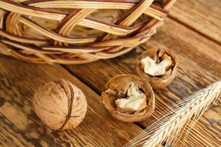 Close-up walnuts, wheat ear and wicker basket on old wooden boards. Shallow depth of field. Top...