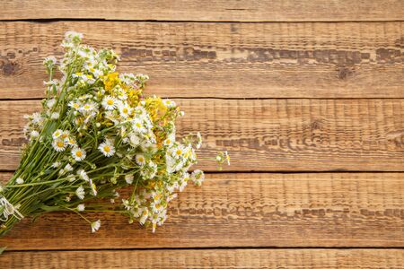 Bouquet of wildflowers with chamomiles on old wooden boards. Top view with copy space.の写真素材