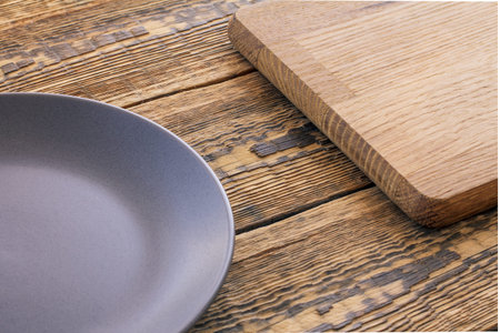 Empty gray porcelain dish and wood cutting board on brown wooden boardsの写真素材