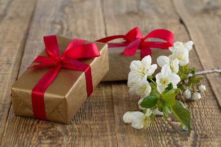 Gift boxes wrapped with red ribbons decorated with flowers of jasmine on wooden boards. Color tone changed.の写真素材