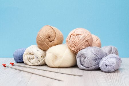 Knitting yarn balls and metal knitting needles on wooden boards and blue background. Knitting concept.の写真素材