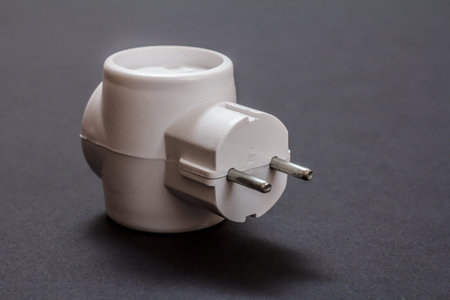 White electrical tee connector with three sockets on a black background.