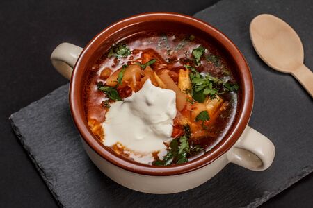 Ukrainian traditional borsch with sour cream in porcelain bowl with wooden spoon on stone board. Top view.の写真素材