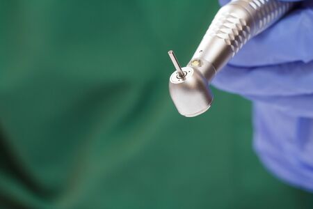 Close-up dentist's hand in a latex glove with high-speed dental hand piece on blurredの写真素材