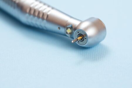 Head of high-speed dental handpiece on blue background. Dental instruments for dental treatment. Medical tools. Close-up view. Shallow depth of field.の写真素材