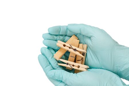 Women's hands in blue latex gloves holding wooden clothespins on a white isolatedの写真素材