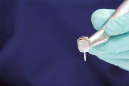 Close-up dentist's hand in a latex glove with high-speed dental handpiece on blurred background. Medical tools concept. Shallow depth of fiel.の写真素材