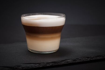 Cup of cappuccino on black stone board and dark background.の写真素材