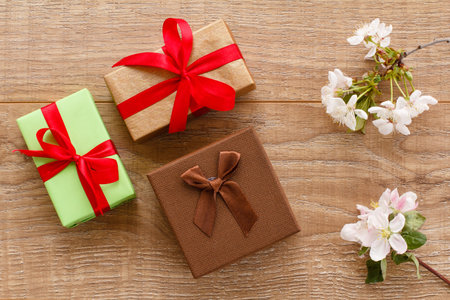 Gift boxes with branches of flowering cherry tree on the wooden background. Top view. Concept of...