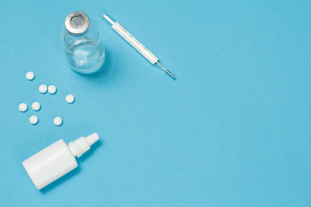 Nasal spray, pills, a glass bottlle and a mercury thermometer. Top view. Treatment kit concept.