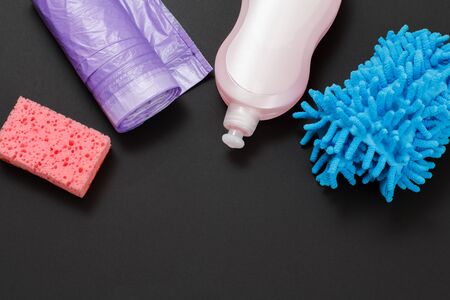 Plastic bottle of washing liquid, rags, garbage bags and a sponge on the black background. Top view. Washing and cleaning set.の写真素材