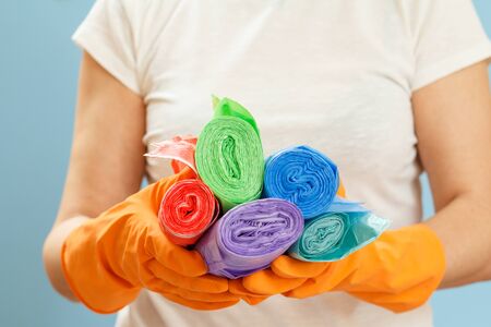 Woman in a white t-shirt holding garbage bags on the blue background. Shallow depth of field. Focus on bags. Washing and cleaning concept.の写真素材