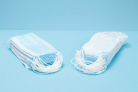 Two stacks of medical protective masks on a blue background. Personal protective equipment against...