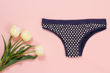 Black cotton panties with tulip flowers on a pink background. Woman underwear set. Top view.