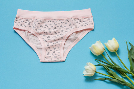 Cotton panties with tulip flowers on a blue background. Woman underwear set. Top view.