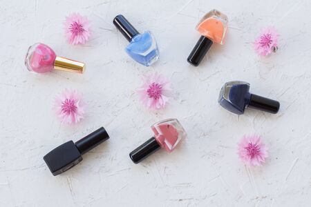 Bottles with nail polish and pink flowers on a white background. Women cosmetics and accessories. Top view.の写真素材