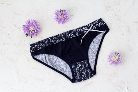Black cotton panties with flower buds on the white structured background. Woman underwear set. Top...