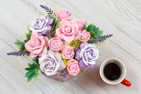 Soap in form of colorful different flowers and a cup of coffee on the gray wooden background. Top view.の写真素材