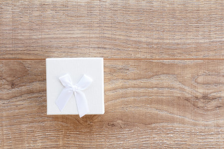 White gift box on the wooden boards. Top view. Concept of giving a gift on holidays.