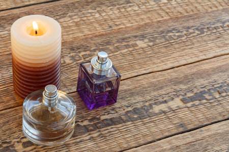 Perfumes and a burning candle on the old wooden boards. Top view. Holiday concept.