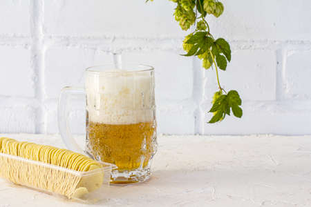 Glass mug of beer with potato chips and a hop branch on the white background.の写真素材