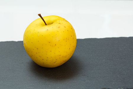 Yellow apple fruit on the black stone board and white background. Organic fruits.の写真素材