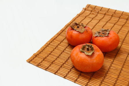 Delicious ripe persimmon fruits on the bamboo napkin. Organic fruits.の写真素材