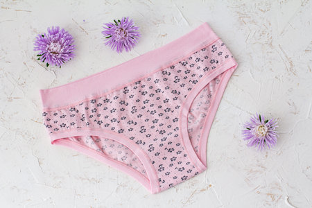 Pink cotton panties with flower buds on the white structured background. Woman underwear set. Top...