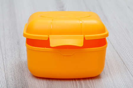 Yellow plastic lunch box on the gray wooden background.の写真素材