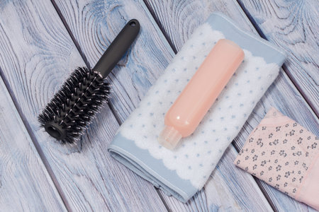 Bottle of shampoo, a towel, a comb and a women folded cotton panties on a wooden background. Women...