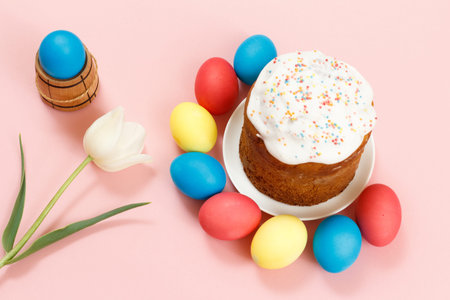 Easter cake on a plate with colorful Easter eggs and a tulip flower on the pink background. Traditional orthodox christian easter food. Top view.の写真素材