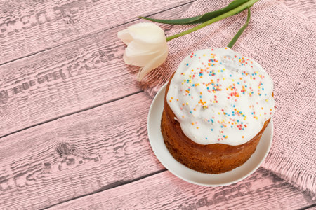 Easter cake on a plate with a tulip flower on the pink sackcloth and boards. Traditional orthodox...
